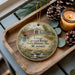 A wooden tray with a decorative ornament featuring a scenic image of the Union covered bridge in Missouri, accompanied by pine cones and a lit candle.