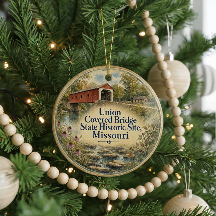 A round ornament hanging on a Christmas tree, featuring a painting of a covered bridge and the text "Union Covered Bridge State Historic Site, Missouri".
