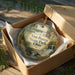 A decorative ornament in a box, featuring a scenic landscape with a bridge and waterfalls, with the text "Van Buren State Park, Ohio" printed on it.
