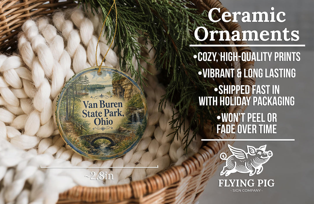 Ceramic ornaments, featuring a design of Van Buren State Park, Ohio, hanging in a basket with pine branches.