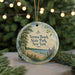 A round ornament with a beach scene and text, hanging on a string.