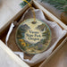A decorative ornament in a box, featuring a scenic landscape with mountains, a waterfall, and flowers.