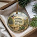 A decorative ornament with a patriotic design, featuring an American flag, a cactus, and a scenic landscape, placed in a box with pine branches.