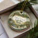 A decorative ornament in a box, featuring a scenic image of Village Creek State Park, Texas.
