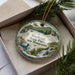 A decorative ornament featuring a scenic landscape of Wadleigh State Park, New Hampshire, with a waterfall and pine trees.