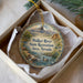 A decorative ornament in a box, featuring a scenic landscape with mountains, trees, and a river.