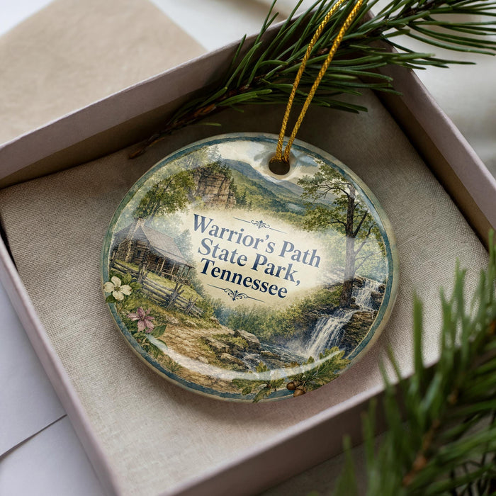 A decorative ornament in a box, featuring a scenic landscape with a waterfall and pine trees.