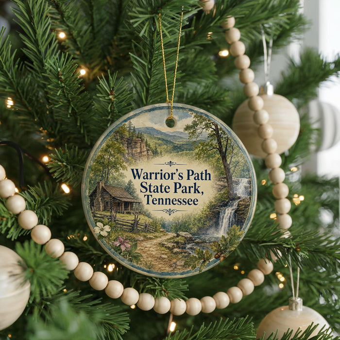 A round ornament hanging on a Christmas tree, featuring a scenic image of a cabin and a waterfall in Tennessee.