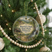 A round ornament hanging on a Christmas tree, featuring a scenic image of a cabin and a waterfall in Tennessee.