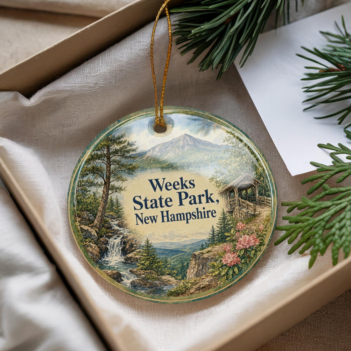 A decorative ornament with a scenic landscape of Weeks State Park in New Hampshire, featuring a waterfall and pine trees.