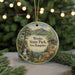 A circular ornament with a scenic landscape of Weeks State Park in New Hampshire, featuring a waterfall, pine trees, and a wooden cabin.