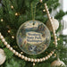 A round ornament hanging on a Christmas tree, featuring a scenic landscape with a waterfall and mountains.