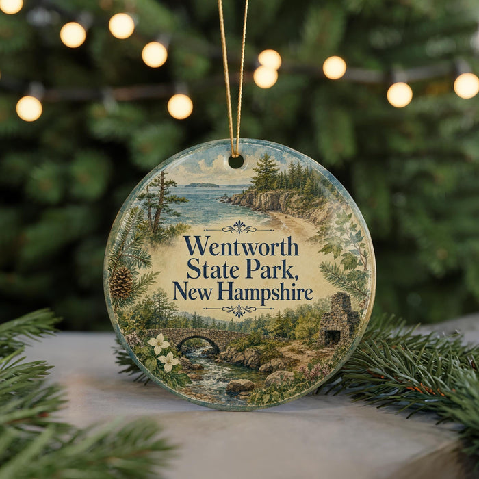 A round ornament with a scenic landscape of Wentworth State Park, New Hampshire, featuring a bridge, pine trees, and a river.