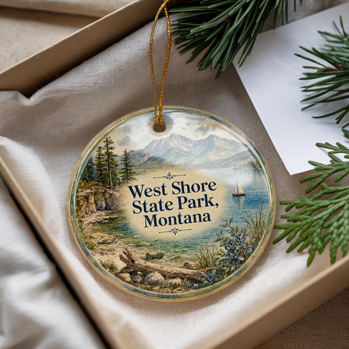 A decorative ornament with a scenic landscape of mountains, pine trees, and a lake, featuring the text "West Shore State Park, Montana" on it.