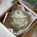 A round ornament with a scenic landscape of Westcott Beach State Park, New York, displayed in a box with a white tissue paper lining.