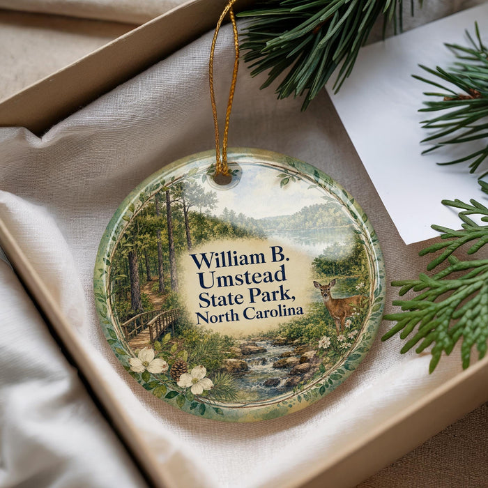 A decorative ornament with a scenic image of William B. Umstead State Park, North Carolina, hanging from a string.
