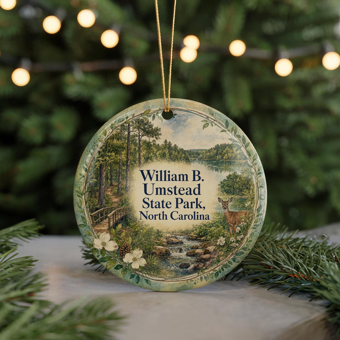 A round ornament with a scenic image of William B. Umstead State Park, North Carolina, featuring a deer in the foreground and a forest landscape in the background.