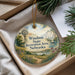 A decorative ornament with a windmill and a sailboat, surrounded by a scenic landscape, is displayed in a box with pine branches.