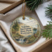 A decorative ornament with a scenic landscape featuring a waterfall, pine trees, and wildlife, including a deer and a bird, is displayed in a box.