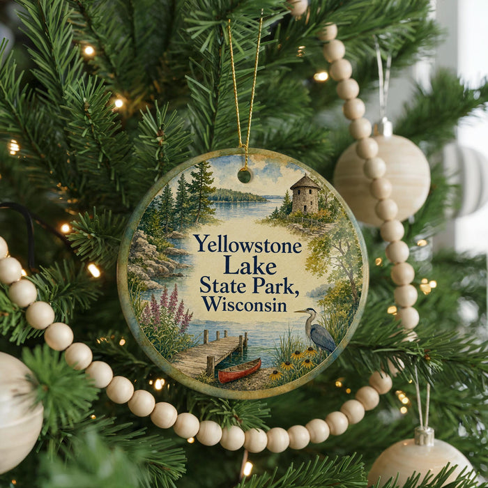 A round ornament hanging on a Christmas tree, featuring a scenic landscape with a lake, a dock, and a bird.