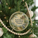 A round ornament hanging on a Christmas tree, featuring a scenic image of York River State Park, Virginia.