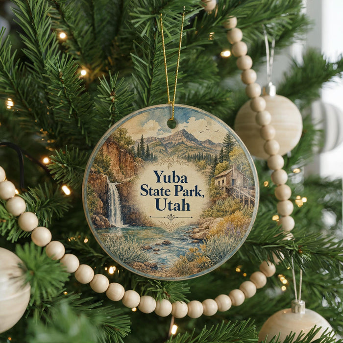 A round ornament hanging on a Christmas tree, featuring a scenic landscape with a waterfall and mountains.