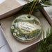 A decorative ornament with a scenic landscape of A.H. Stephens State Park, Georgia, featuring a bridge and pine trees.