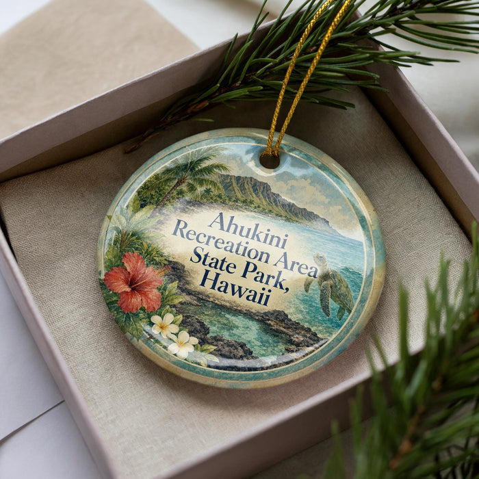 A decorative ornament with a tropical island landscape and hibiscus flowers, placed in a box with pine branches.