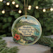 A round ornament with a tropical beach scene and text, hanging on a string.