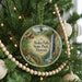A round ornament hanging on a Christmas tree, featuring a scenic image of Akaka Falls State Park in Hawaii.