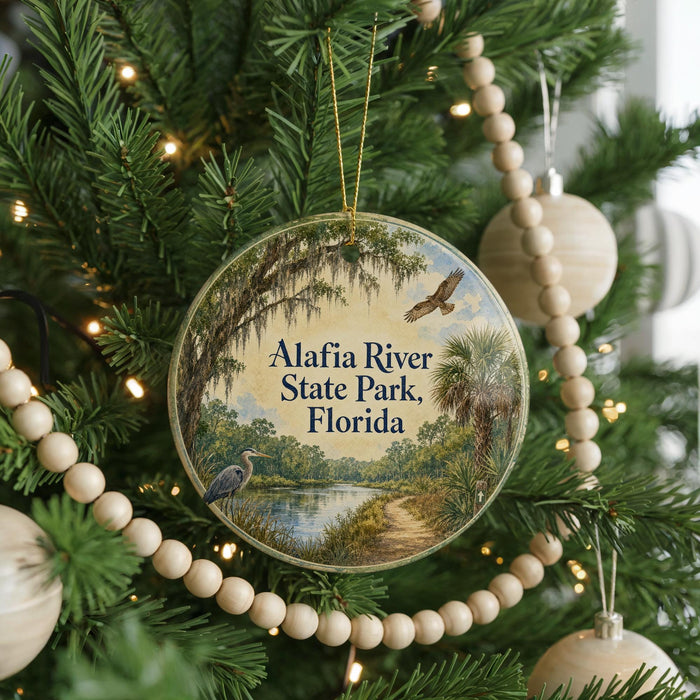 A circular ornament hanging on a Christmas tree, featuring a scenic image of the Alafia River State Park in Florida.