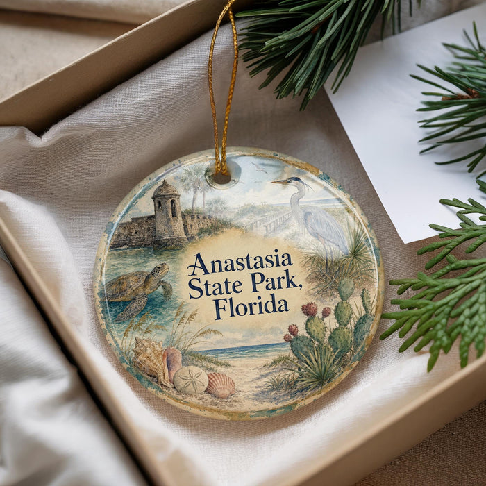 A decorative ornament with a beach scene and a bird, placed in a box with pine branches.