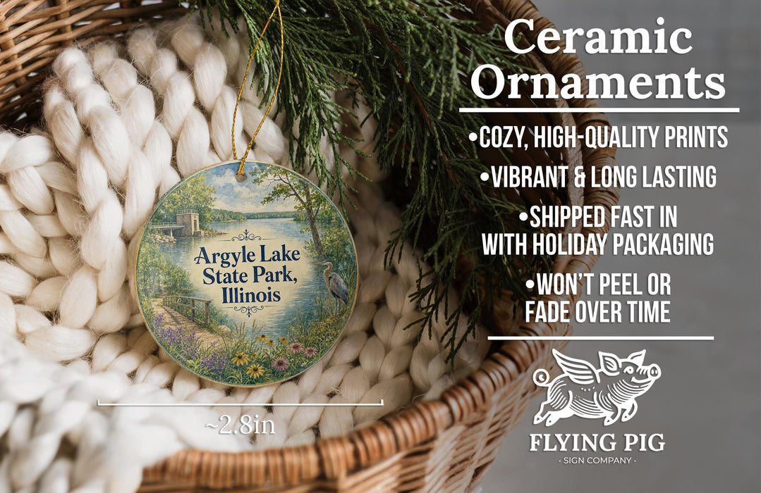 Ceramic ornaments, specifically Argyle Lake State Park, Illinois ornaments, are displayed in a basket with pine branches. The text highlights the ornaments as "cozy, high-quality prints, vibrant and long lasting, shipped fast in with holiday packaging, won't peel or fade over time, and the size is 2.8in".