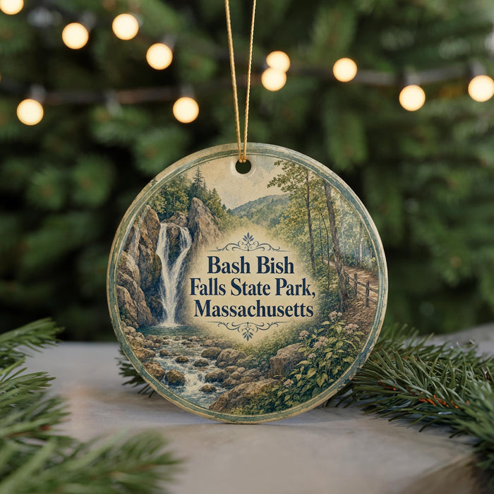 A round ornament with a scenic image of a waterfall and forest, surrounded by Christmas lights.