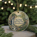 A round ornament with a scenic image of a waterfall and forest, surrounded by Christmas lights.