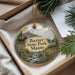 A decorative ornament in a box, featuring a moose and a scenic landscape with a mountain backdrop.