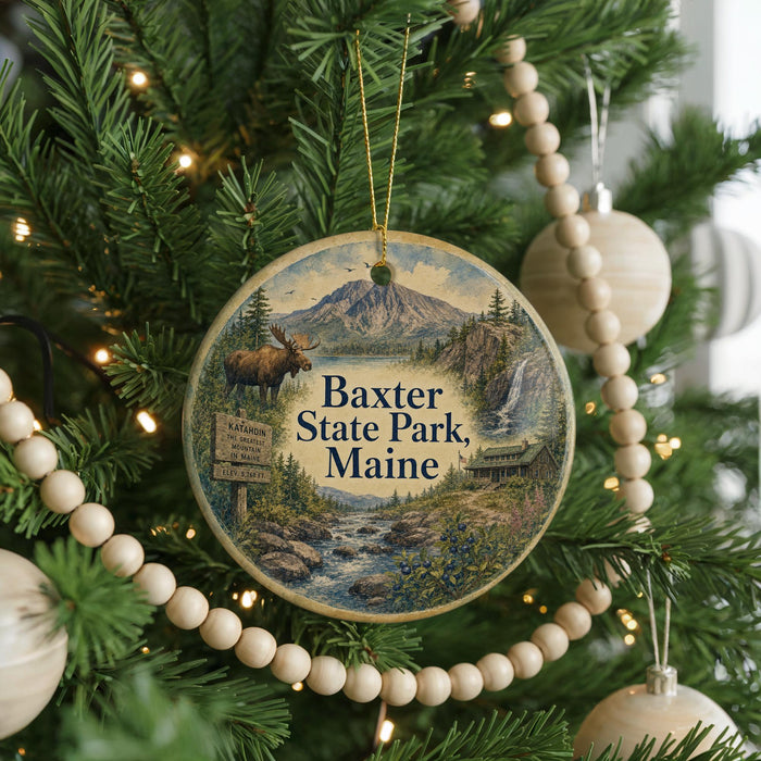 A circular ornament hanging on a Christmas tree, featuring a scenic image of Baxter State Park in Maine.