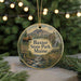 A circular ornament featuring a scenic landscape with a moose, mountains, and a river, hanging from a string.