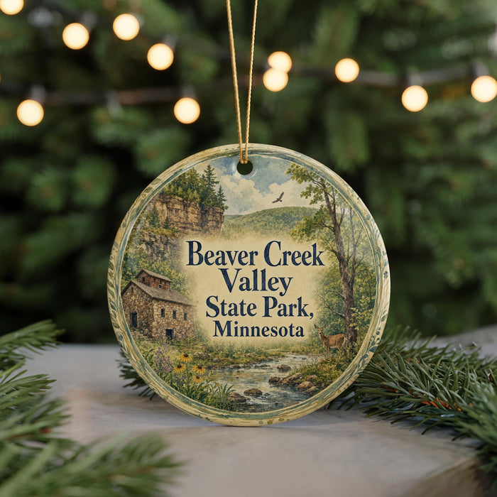 A round ornament with a painting of Beaver Creek Valley State Park in Minnesota, featuring a house, trees, and a stream.