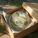 A round ornament in a brown box, featuring a scenic image of Beaver Creek Valley State Park in Minnesota.
