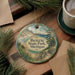 A round ornament with a scenic landscape of Benzie State Park, Michigan, featuring a lake, mountains, and pine trees.