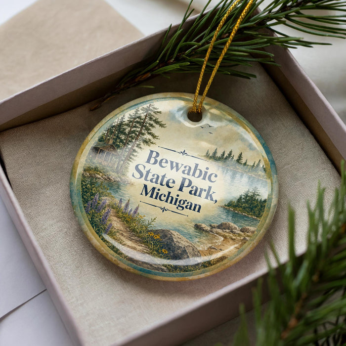 A decorative ornament with a scenic landscape of Bewabic State Park, Michigan, featuring a lake, pine trees, and mountains.