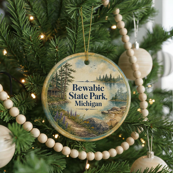 A round ornament hanging on a Christmas tree, featuring a scenic image of Bewabic State Park, Michigan.