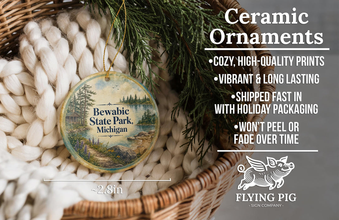 Ceramic ornaments, specifically Bewabic State Park Michigan ornaments, are displayed in a basket with pine branches. The text highlights the ornaments as "cozy, high-quality prints, vibrant and long lasting, shipped fast in with holiday packaging, won't peel or fade over time".
