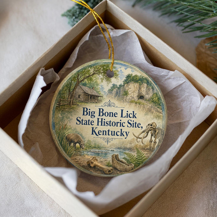 A decorative ornament in a box, featuring a scenic landscape with a house, trees, and wildlife.