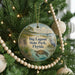 A round ornament hanging on a Christmas tree, featuring an illustration of a beach scene with a bird, palm tree, and a turtle.