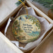 A decorative ornament in a box, featuring a lighthouse, palm trees, and a turtle, with the text "Bill Baggs Cape Florida State Park, Florida" printed on it.
