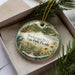 A decorative ornament in a box, featuring a scenic image of Blackwater River, State Park, Florida.