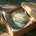 A decorative ornament in a brown box, featuring a scenic image of Blue Springs State Park in Alabama.