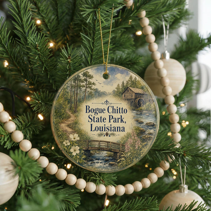 A round ornament hanging on a Christmas tree, featuring a scenic image of a bridge and a river surrounded by trees and greenery.